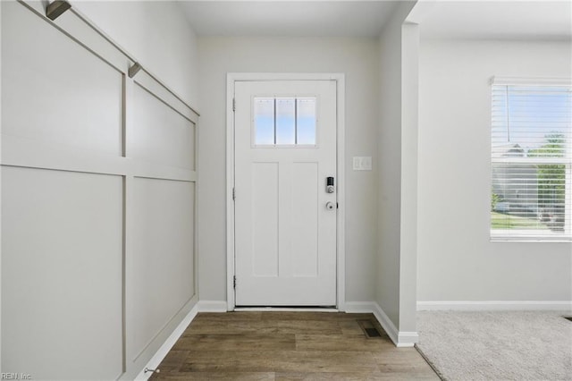 doorway with a healthy amount of sunlight, baseboards, wood finished floors, and visible vents