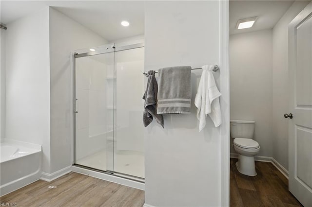 full bathroom featuring a bath, wood finished floors, toilet, and a shower stall