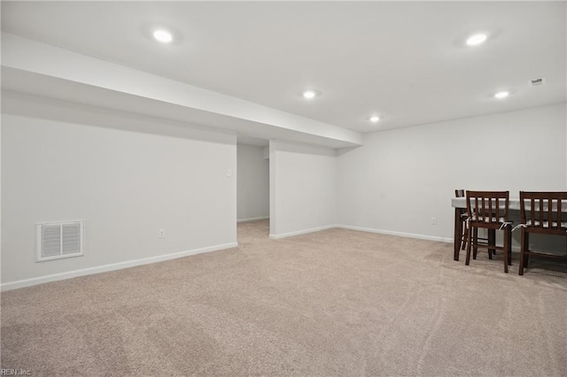 finished below grade area featuring visible vents, recessed lighting, baseboards, and light carpet