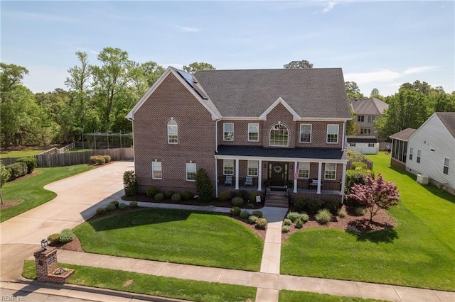 view of front facade featuring fence, concrete driveway, a porch, and a front lawn