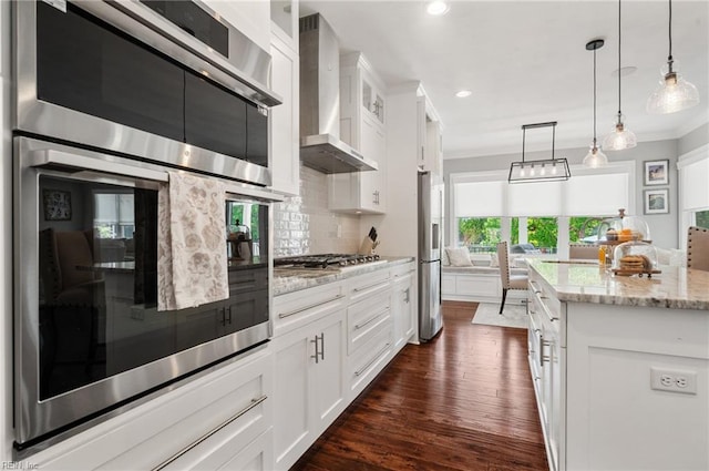 kitchen with tasteful backsplash, white cabinets, stainless steel appliances, wall chimney exhaust hood, and dark wood-type flooring