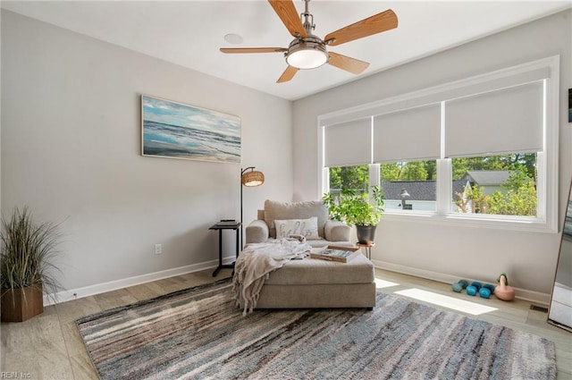 living area featuring baseboards, ceiling fan, and wood finished floors