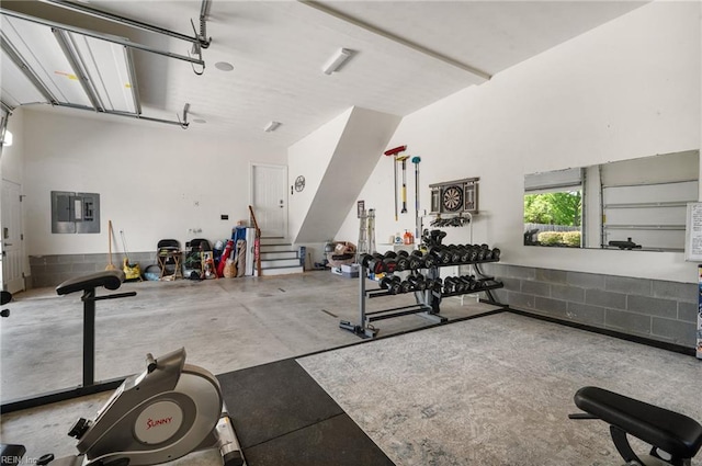 exercise room featuring electric panel and a garage