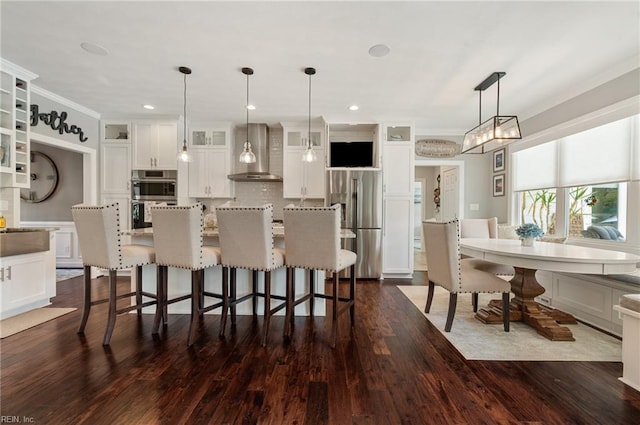 kitchen featuring crown molding, appliances with stainless steel finishes, wall chimney exhaust hood, and white cabinetry