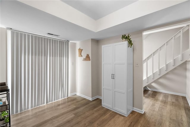 foyer entrance with stairs, baseboards, visible vents, and wood finished floors