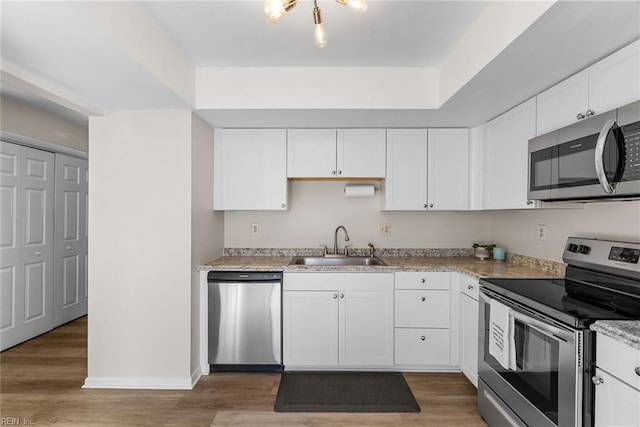 kitchen featuring stainless steel appliances, white cabinetry, a sink, and light wood-style floors