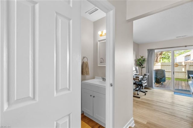 hallway with a sink, light wood-style flooring, and visible vents