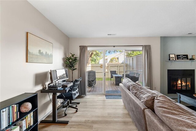 office space featuring visible vents, light wood-style flooring, baseboards, and a large fireplace