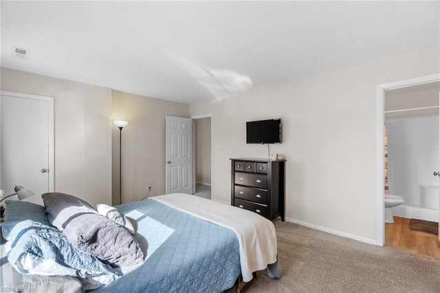 carpeted bedroom with baseboards, visible vents, and ensuite bathroom