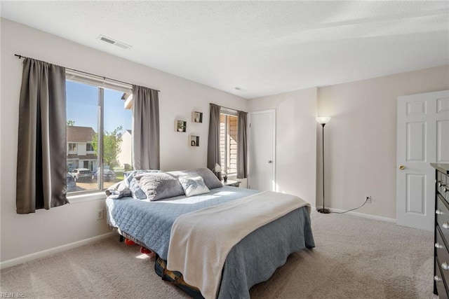 carpeted bedroom with a textured ceiling, baseboards, and visible vents