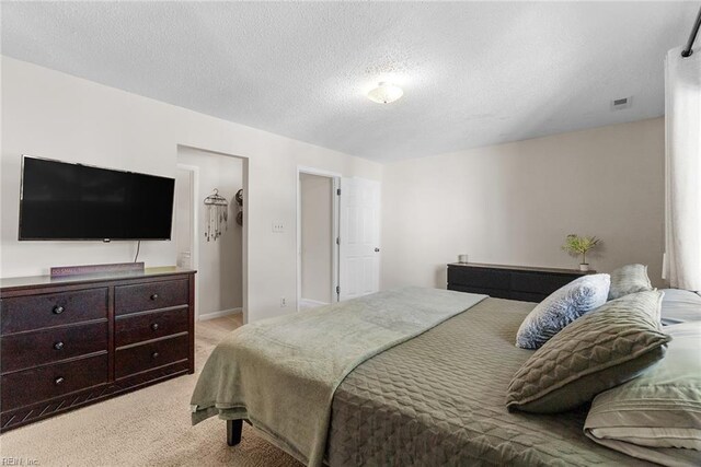 bedroom featuring light carpet, a textured ceiling, and visible vents