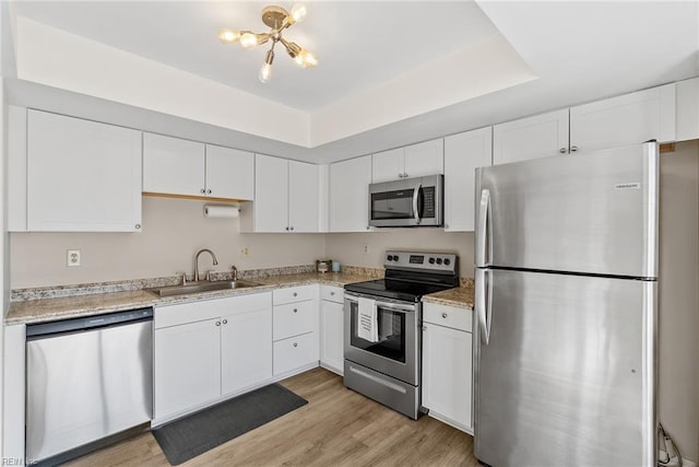 kitchen with white cabinets, a notable chandelier, a sink, light wood-style floors, and stainless steel appliances