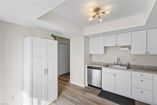 kitchen featuring stainless steel dishwasher, light wood-style floors, light countertops, white cabinetry, and a sink
