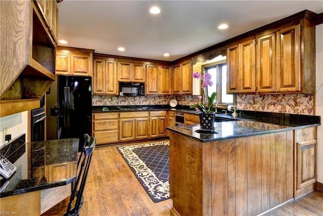 kitchen with brown cabinetry, open shelves, black appliances, a peninsula, and light wood-style floors