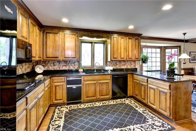 kitchen featuring brown cabinets, a sink, a peninsula, decorative backsplash, and black appliances
