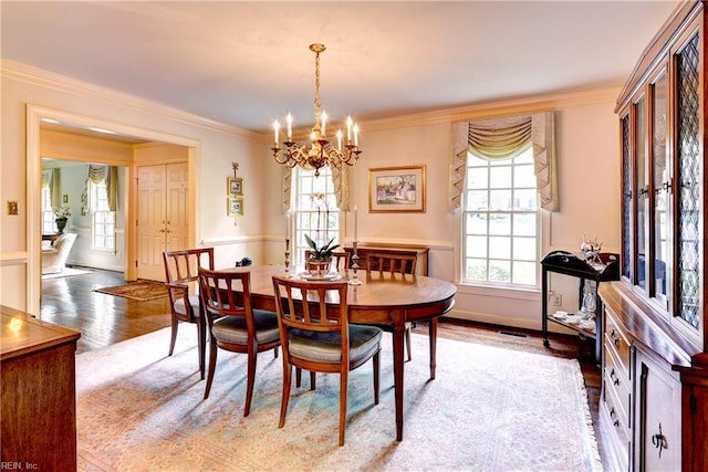 dining area featuring a notable chandelier, ornamental molding, wood finished floors, and visible vents