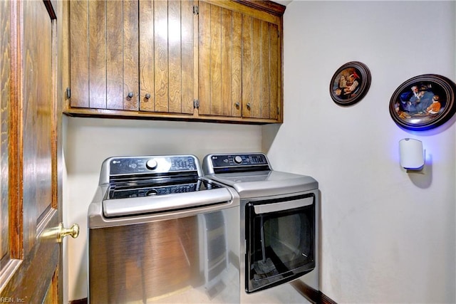 clothes washing area featuring independent washer and dryer and cabinet space