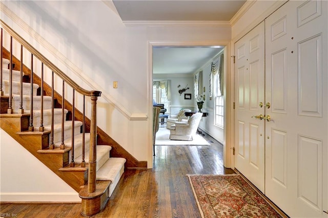 foyer entrance featuring baseboards, dark wood finished floors, ornamental molding, and stairway