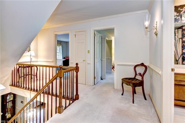 hallway with baseboards, ornamental molding, carpet, and an upstairs landing