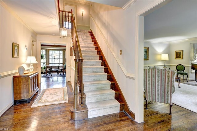 stairs with ornamental molding and wood finished floors
