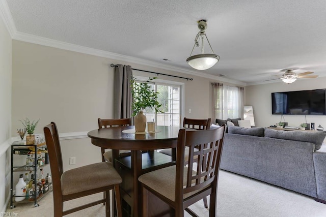 dining space featuring ceiling fan, visible vents, light carpet, and ornamental molding
