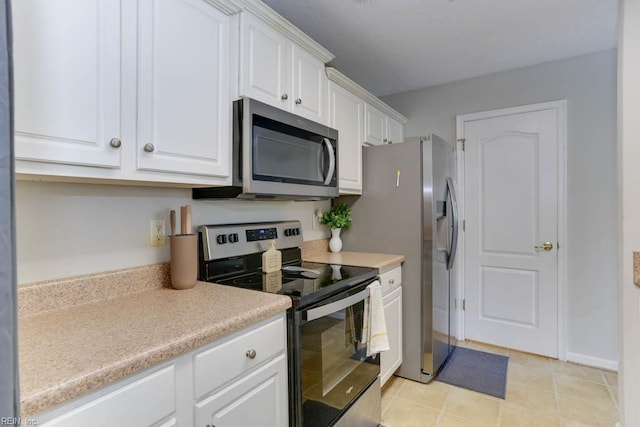 kitchen with light tile patterned flooring, baseboards, light countertops, white cabinetry, and stainless steel appliances