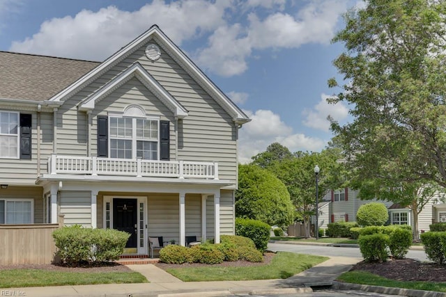 townhome / multi-family property with covered porch and a balcony