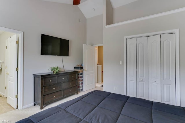 bedroom with a closet, light carpet, baseboards, high vaulted ceiling, and a ceiling fan