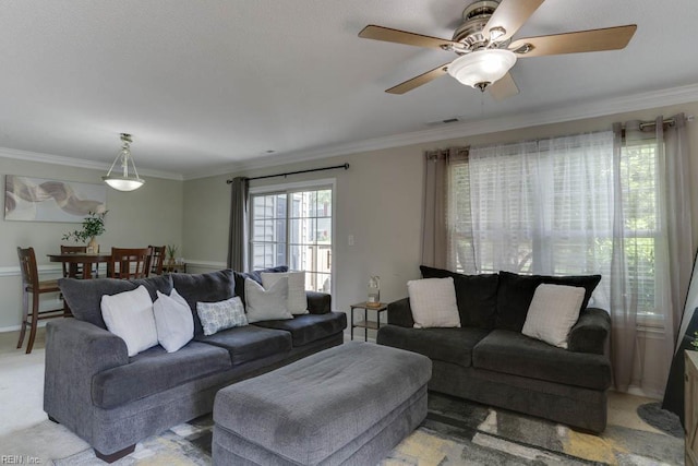 living room with ceiling fan, visible vents, crown molding, light colored carpet, and baseboards