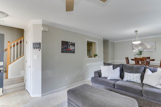 living area featuring baseboards, ornamental molding, a ceiling fan, and stairs