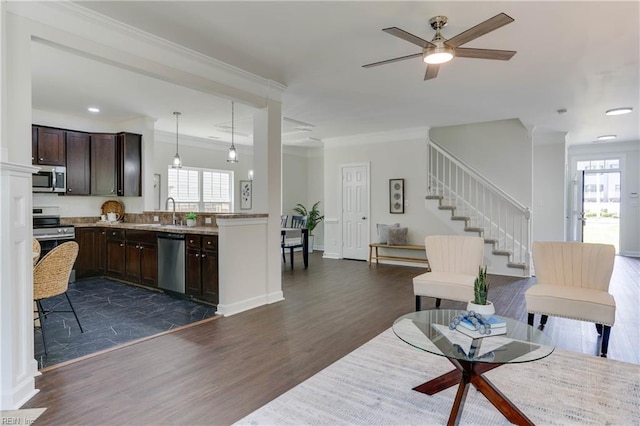living room with plenty of natural light, dark wood-style flooring, crown molding, and stairway