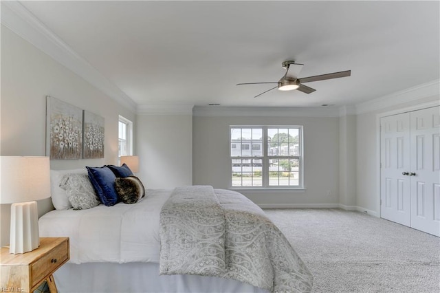 bedroom with ceiling fan, crown molding, baseboards, a closet, and carpet