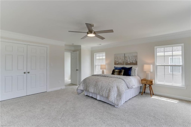 carpeted bedroom featuring crown molding, baseboards, ceiling fan, and a closet