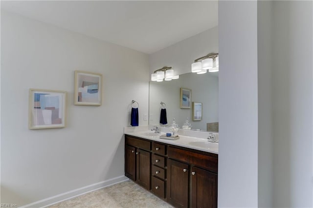 full bathroom featuring a sink, baseboards, and double vanity