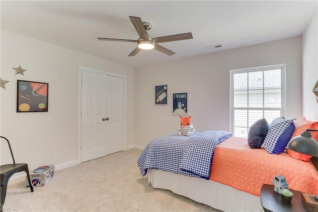 bedroom with visible vents, a closet, baseboards, ceiling fan, and light colored carpet