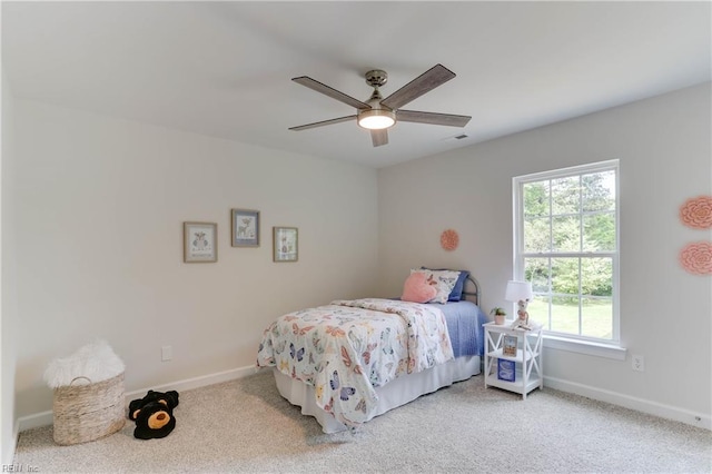 carpeted bedroom featuring a ceiling fan, baseboards, and multiple windows