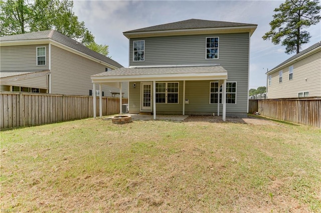 rear view of house featuring a lawn, a fire pit, and a fenced backyard