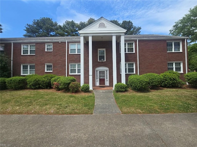greek revival inspired property featuring a front lawn and brick siding