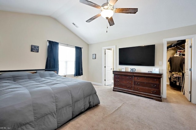 bedroom with visible vents, a ceiling fan, a walk in closet, carpet flooring, and vaulted ceiling
