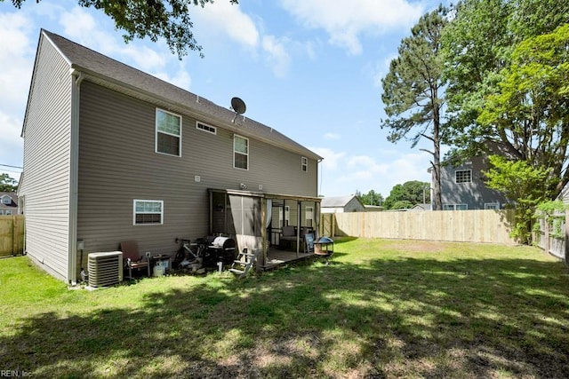 rear view of house featuring a lawn, central AC, and a fenced backyard