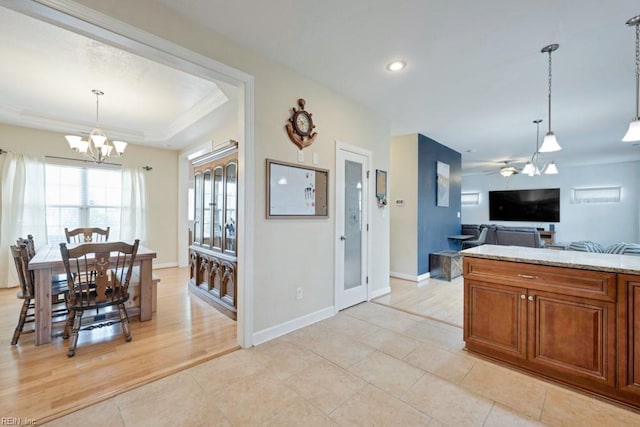 kitchen featuring light tile patterned floors, baseboards, brown cabinets, and decorative light fixtures