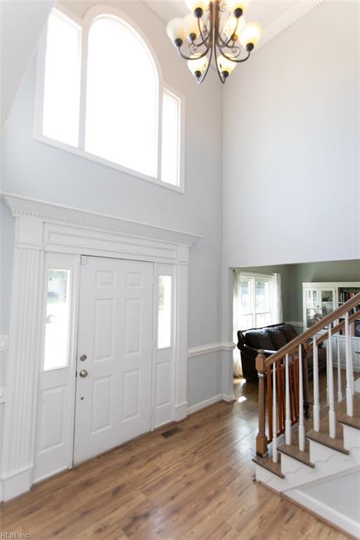 foyer entrance with a high ceiling, wood finished floors, a notable chandelier, and a wealth of natural light