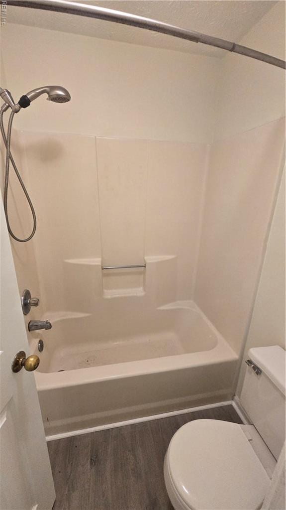 bathroom with toilet, shower / bath combination, and wood finished floors