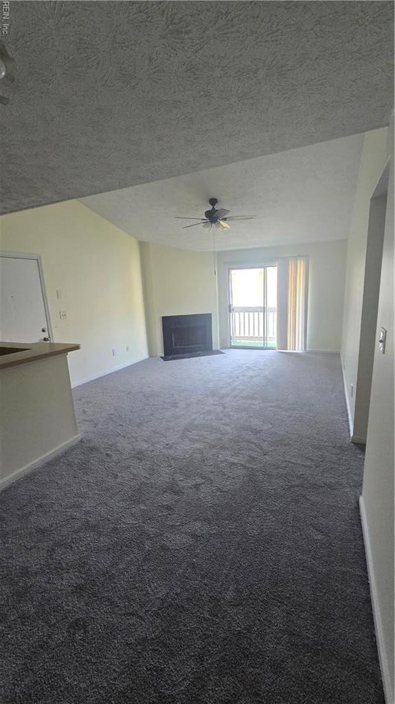 unfurnished living room featuring carpet floors, a ceiling fan, a textured ceiling, and a fireplace
