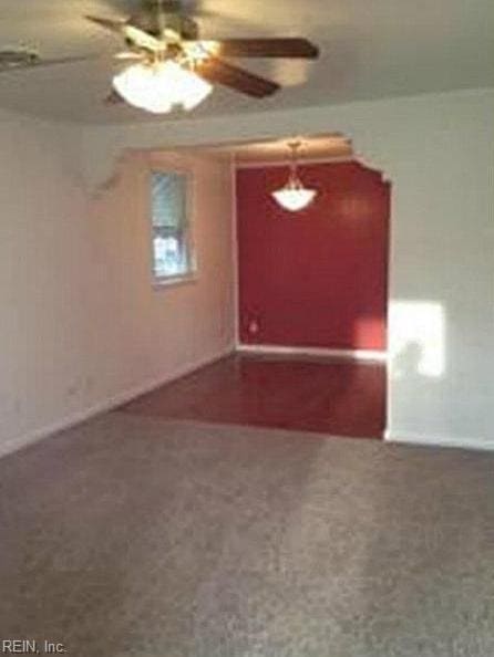 carpeted spare room featuring baseboards and a ceiling fan