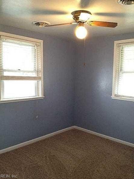 carpeted spare room with ceiling fan, visible vents, and baseboards