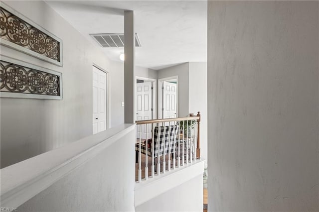 hall with visible vents and an upstairs landing
