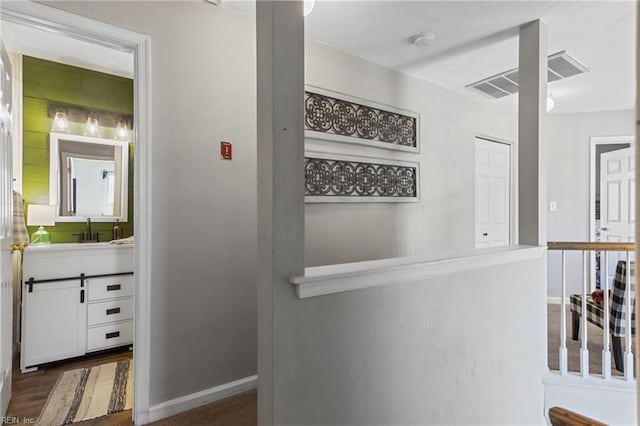corridor featuring a sink, baseboards, dark wood-style floors, and visible vents