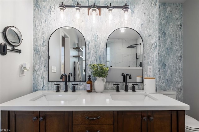 bathroom featuring double vanity, toilet, and a sink
