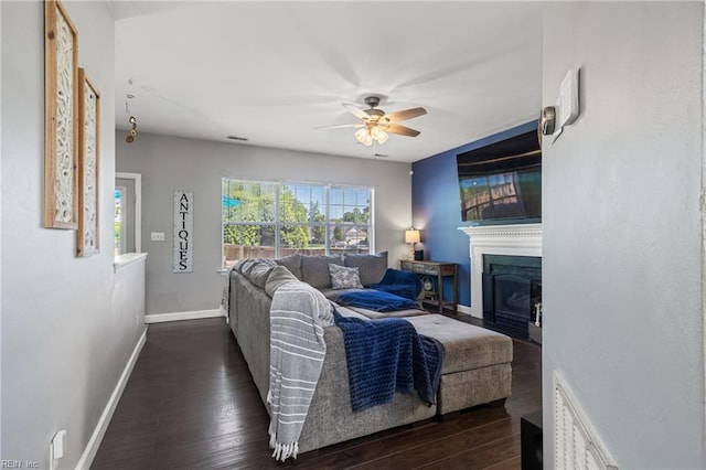 living room featuring baseboards, ceiling fan, dark wood-style floors, and a fireplace